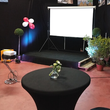 Décor de soirée de séminaire avec scène, écran géant et table cocktail