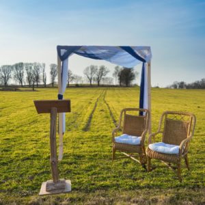 Arche et pupitre en bois marron avec deux fauteuils en osier et voilage bleu roi