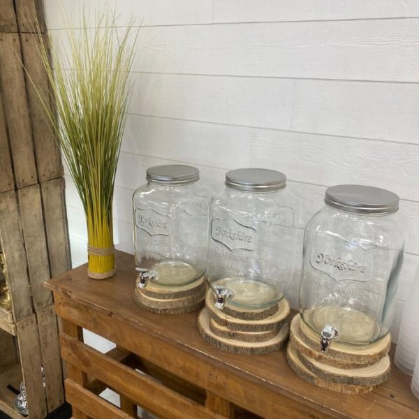 Fontaines à boissons avec robinets sur un meuble en palettes et une plante verte