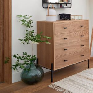 Vase en verre type dame jeanne couleur vert foncé avec plante et meuble en bois